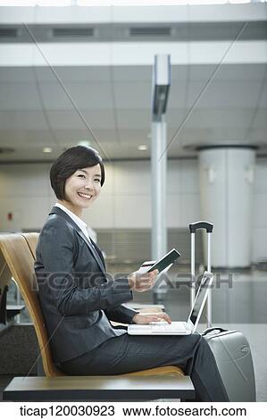 Stock Image - a businesswoman using laptop in the airport. Fotosearch