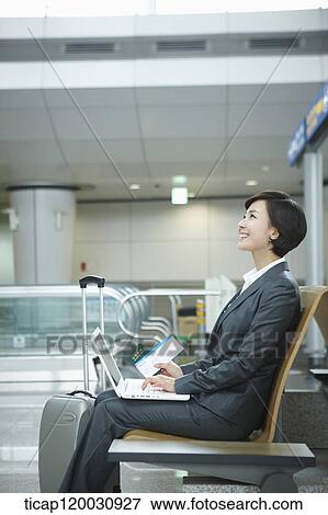 Stock Photo - a businesswoman using laptop in the airport. Fotosearch