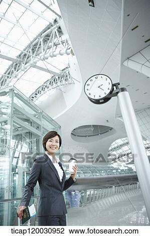 Stock Image - a businesswoman walking with a suitcase in the airport. Fotosearch