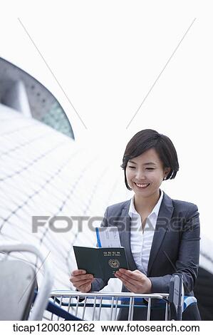 Stock Image - a businesswoman with baggage cart at the airport. Fotosearch