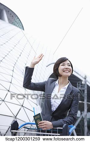 Stock Photo - a businesswoman with baggage cart at the airport. Fotosearch