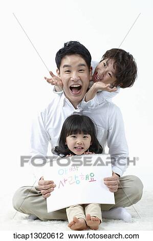 Stock Image - a daughter sitting in fathers lap and holding a notebook. Fotosearch