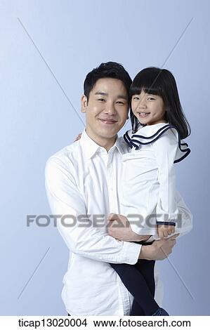 Picture - a father holding daughter in blue background. Fotosearch