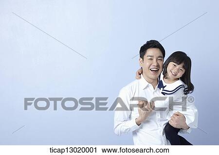 Stock Image - a father holding daughter in blue background. Fotosearch
