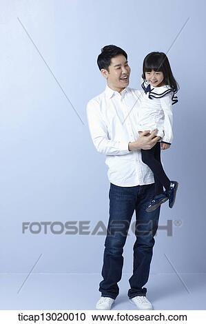 Stock Image - a father holding daughter in blue background. Fotosearch