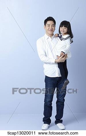 Stock Image - a father holding daughter in blue background. Fotosearch