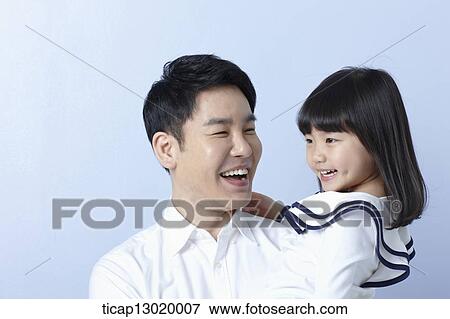 Stock Photo - a father holding daughter in blue background. Fotosearch