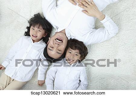 Stock Image - a father lying on the floor with his kids. Fotosearch
