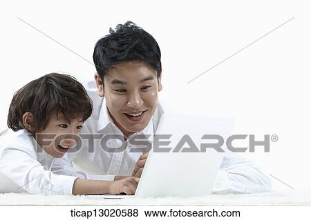 a father lying on the floor with his son while playing on laptop View Large Photo Image Stock Photo - a father lying on the floor with his son while playing on laptop. Fotosearch