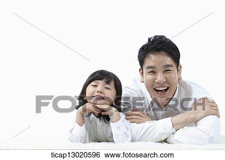 Stock Photograph - a father lying on the floor with his daughter. Fotosearch