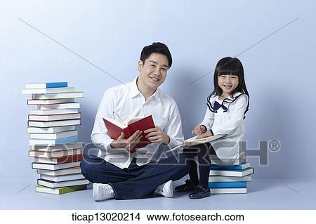 Picture - a father reading books with his daughter. Fotosearch