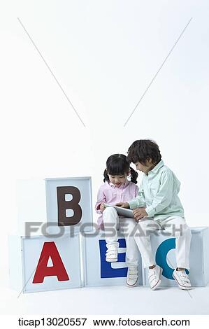Stock Photo - a girl and a boy sitting on boxes with alphabets. Fotosearch