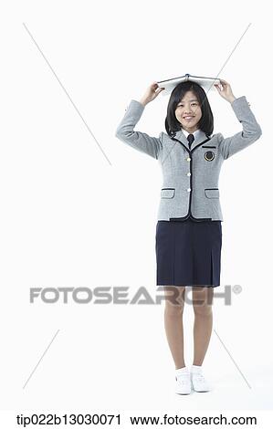 a girl in a school uniform holding a book View Large Photo Image Stock Image - a girl in a school uniform holding a book. Fotosearch