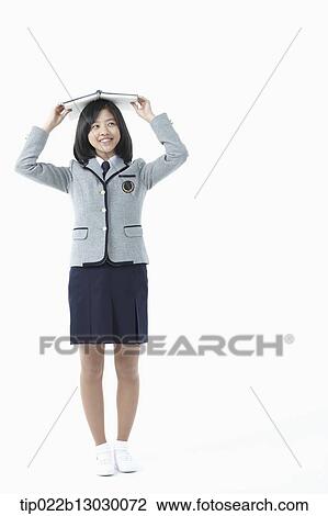 Stock Image - a girl in a school uniform holding a book. Fotosearch
