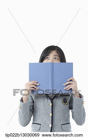 Stock Photo - a girl in a school uniform holding a book. Fotosearch