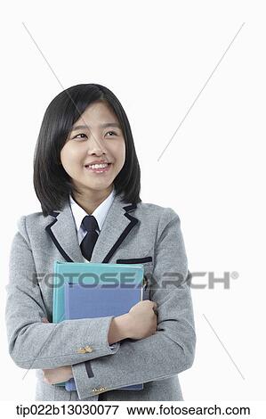 Stock Photo - a girl in a school uniform holding books. Fotosearch