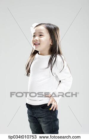 Stock Image - a girl in white shirt and jeans smiling. Fotosearch