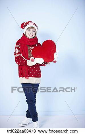 Stock Image - a girl in winter outfit holding a heart. Fotosearch