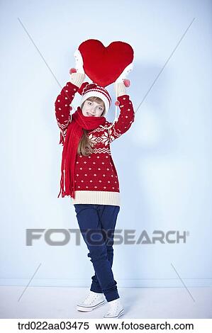 Stock Photography - a girl in winter outfit holding a heart. Fotosearch