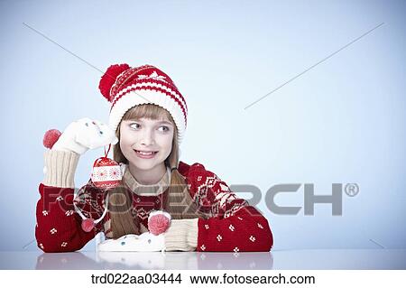 Picture - a girl in winter outfit playing with Christmas decoration. Fotosearch