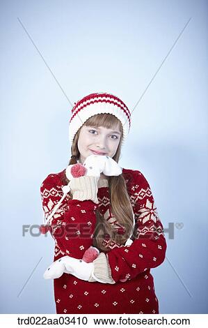 Stock Image - a girl in winter outfit posing on blue background. Fotosearch