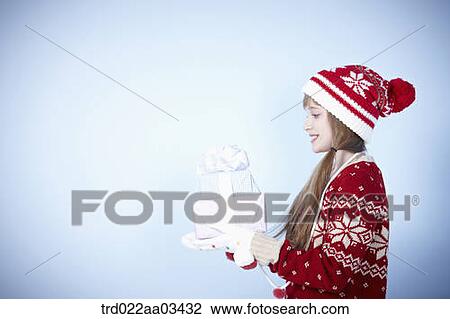 Stock Image - a girl in winter outfit posing with a pile of gifts. Fotosearch