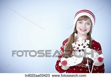 Stock Image - a girl in winter outfit posing with snowflake. Fotosearch
