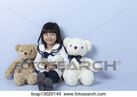 Stock Photo - a girl sitting between teddy bears. Fotosearch