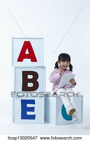 Stock Photo - a girl sitting on boxes with alphabets. Fotosearch