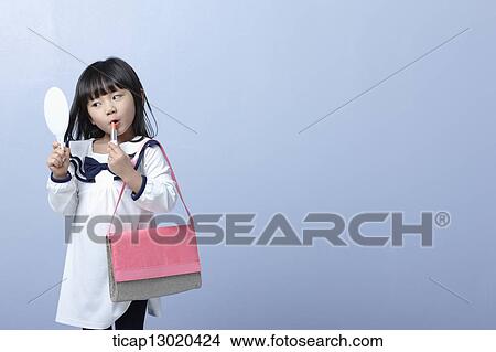 Picture - a girl with big heels and a handbag putting on make up. Fotosearch