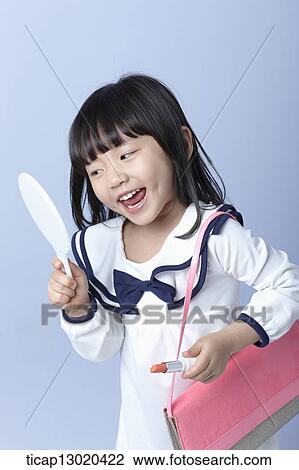 Stock Image - a girl with big heels and a handbag putting on make up. Fotosearch