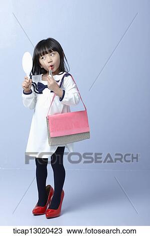Stock Image - a girl with big heels and a handbag putting on make up. Fotosearch