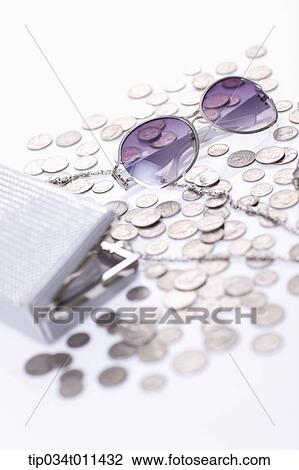 Stock Image - a hand bag next to small coins and sun glasses. Fotosearch