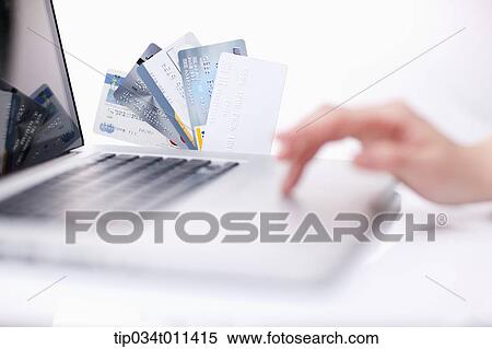 Stock Photography - a hand using a laptop next to cards. Fotosearch