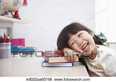 a kid smiling while leaning on a pile of books View Large Photo Image Stock Photograph - a kid smiling while leaning on a pile of books. Fotosearch