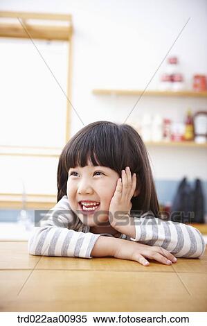 Stock Photography - a kid smiling while sitting at table. Fotosearch