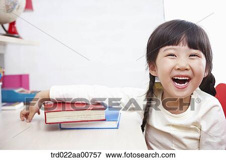 Stock Photo - a kid smiling with a pile of books in front. Fotosearch