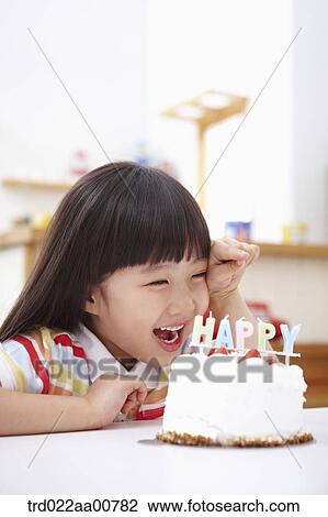 Stock Image - a kid with a birthday cake in front. Fotosearch