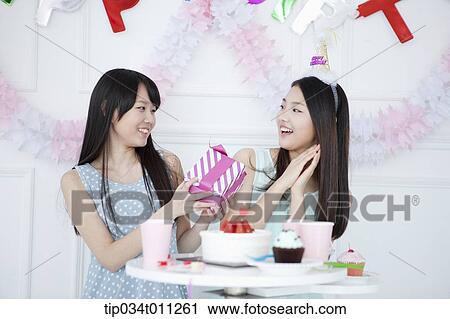 Stock Image - a lady giving a present to her friend. Fotosearch