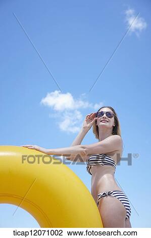 Stock Image - a lady in bikini and beach tube posing in the beach. Fotosearch
