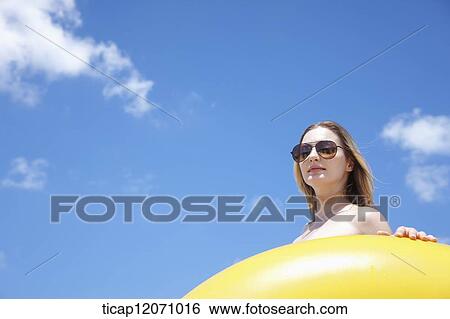 Stock Photograph - a lady in bikini and beach tube under bright sky. Fotosearch