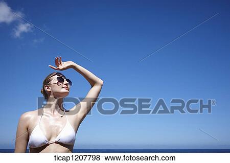 a lady in bikini and sunglasses posing under bright sky View Large Photo Image Stock Photo - a lady in bikini and sunglasses posing under bright sky. Fotosearch