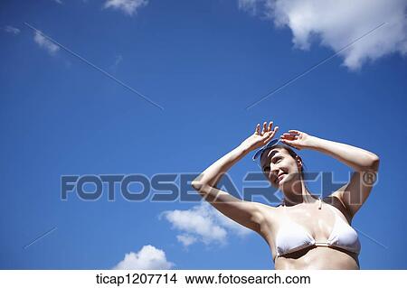 Picture - a lady in bikini and sunglasses under bright sky. Fotosearch