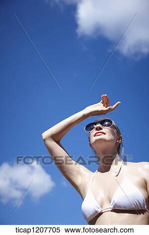 Stock Photography - a lady in bikini and sunglasses under bright sky. Fotosearch