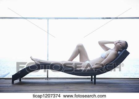 a lady in bikini lying on a beach bed View Large Photo Image Picture - a lady in bikini lying on a beach bed. Fotosearch
