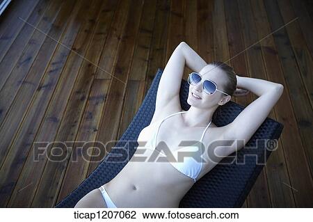 a lady in bikini lying on a beach bed View Large Photo Image Stock Image - a lady in bikini lying on a beach bed. Fotosearch