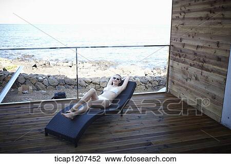 a lady in bikini lying on a beach bed View Large Photo Image Stock Image - a lady in bikini lying on a beach bed. Fotosearch