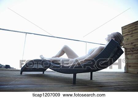 Stock Photo - a lady in bikini lying on a beach bed. Fotosearch