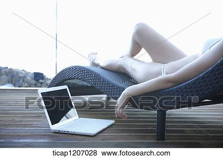 a lady in bikini lying on a beach bed using laptop View Large Photo Image Stock Photo - a lady in bikini lying on a beach bed using laptop. Fotosearch
