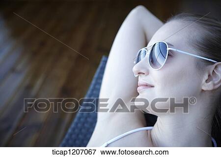 Stock Photo - a lady in bikini lying on a beach bed. Fotosearch